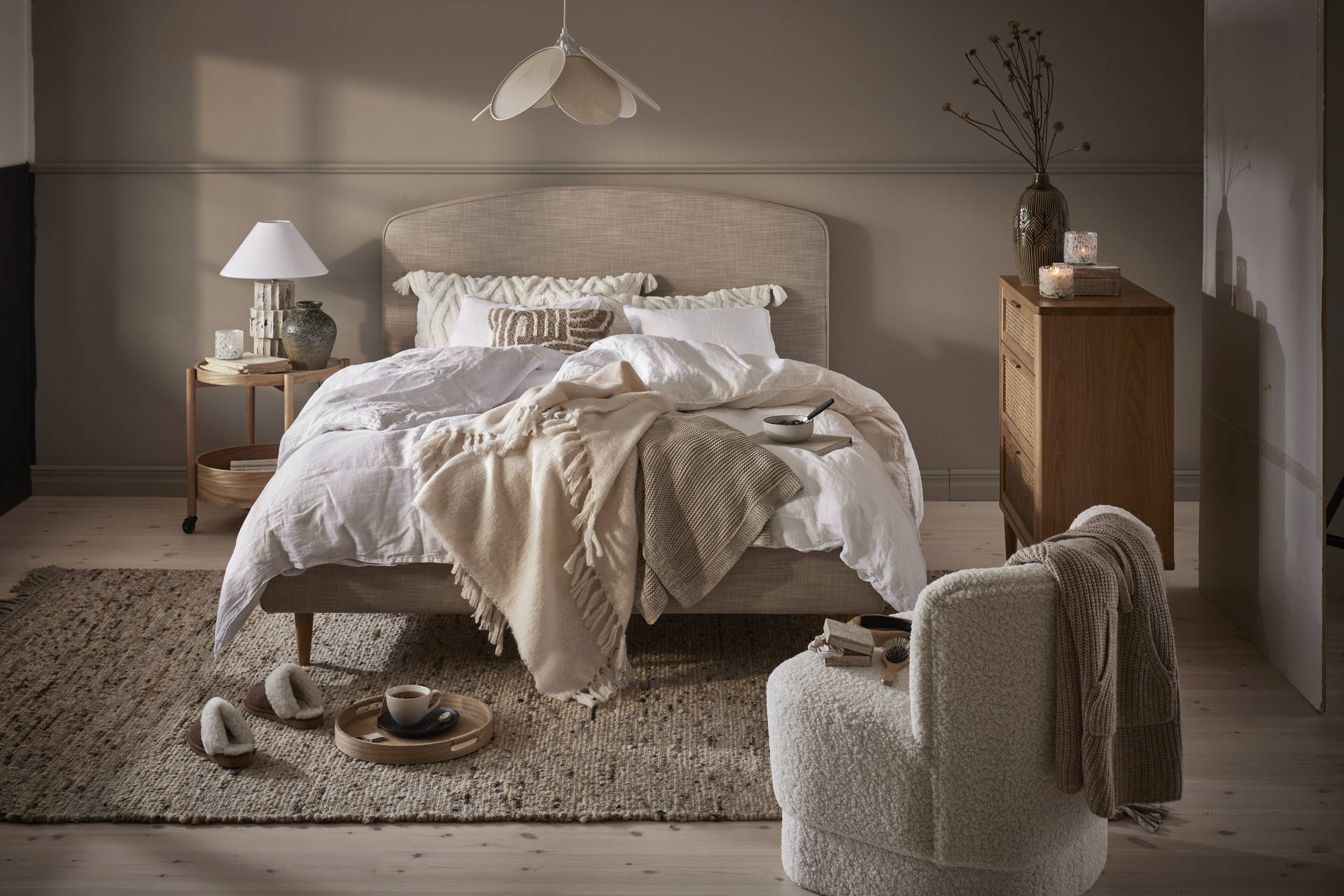 en beige säng bäddad med vita lakan i ett sovrum