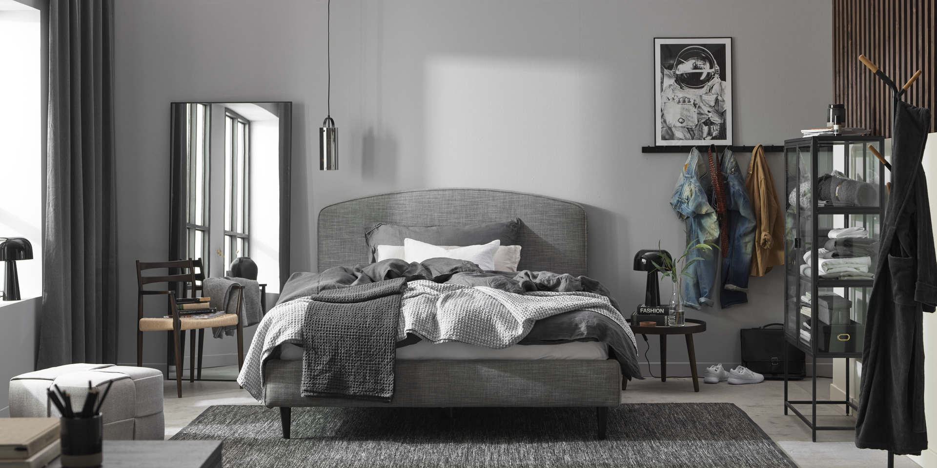 en grå dubbelsäng står i ett sovrum med mörka detaljer
