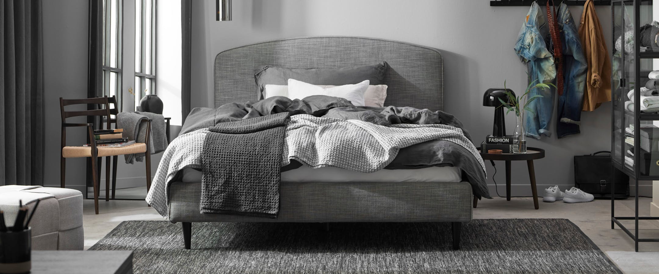en grå dubbelsäng står i ett sovrum med mörka detaljer
