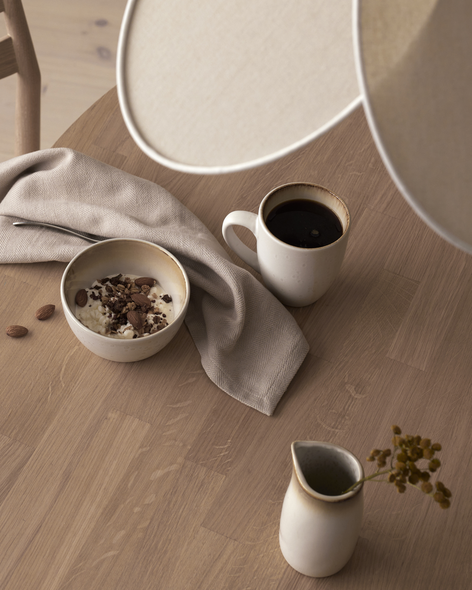 en vit skål och mugg står på ett ekfärgat bord