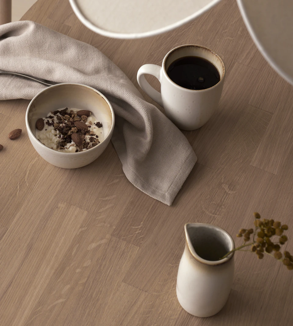 en vit skål och mugg står på ett ekfärgat bord
