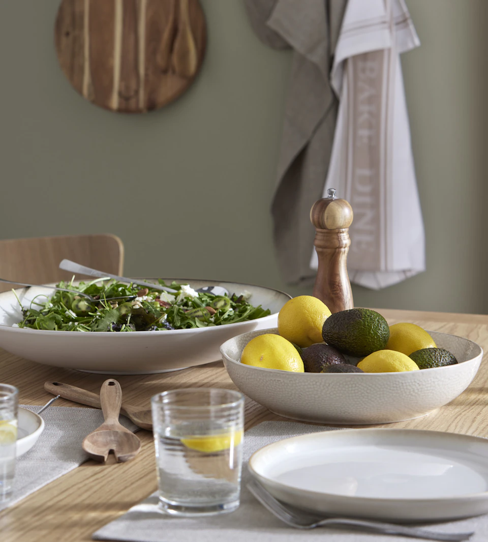 vitt porslin i form av skålar och tallrikar står uppdukade på ett matbord