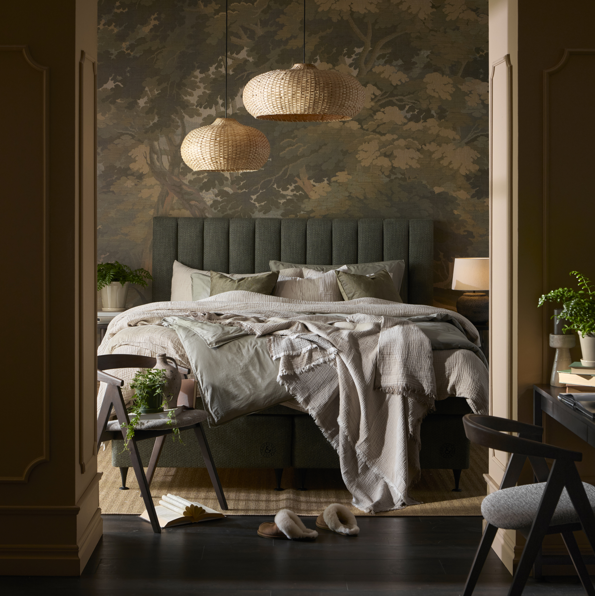 en säng med grön sänggavel och grå och bruna sängkläder står i ett sovrum med en mönstrad grön tapet