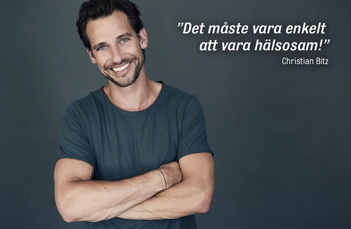 en brunhårig man ler och tittar in i kameran