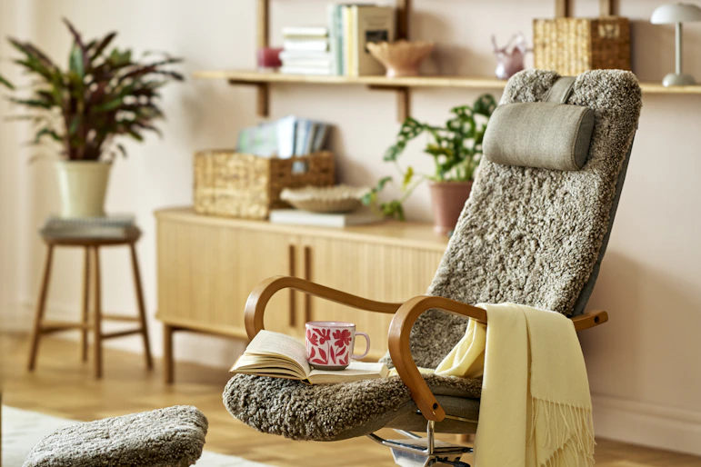 en brun fårskinnsfåtölj står i ett vardagsrum med många ljusa detaljer