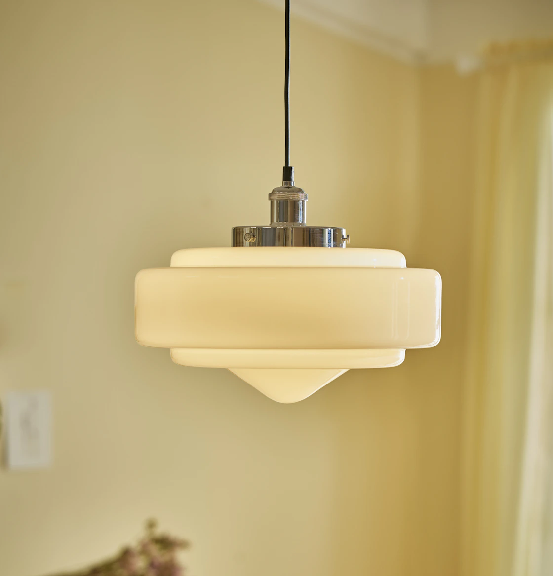 en vit taklampa är tänd och hänger ned framför en gul vägg