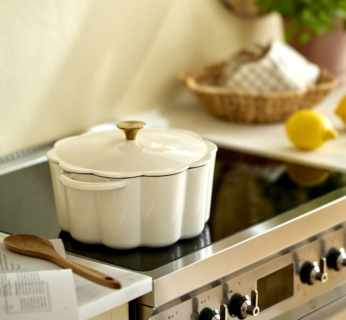 en vit gjutjärnsgryta står på en spis i ett gult kök