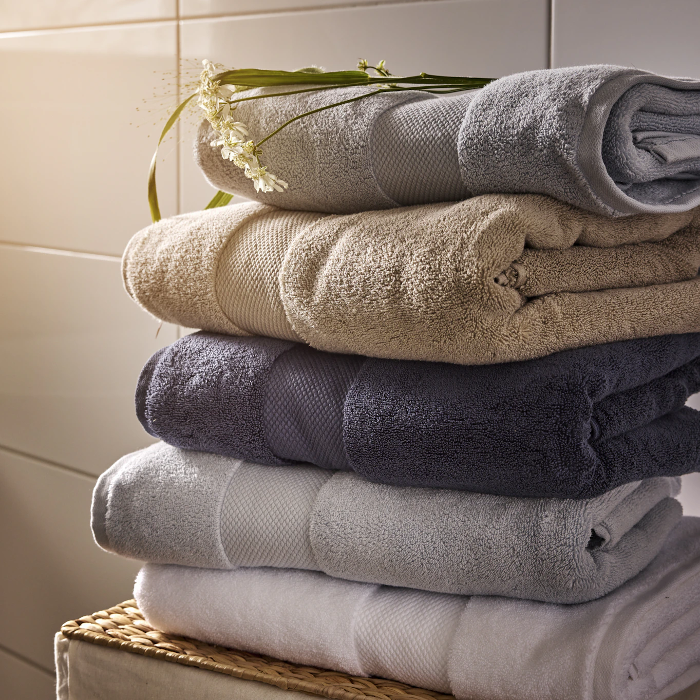 en hög med ihopvikta handdukar i vitt, grått, blått och beiget