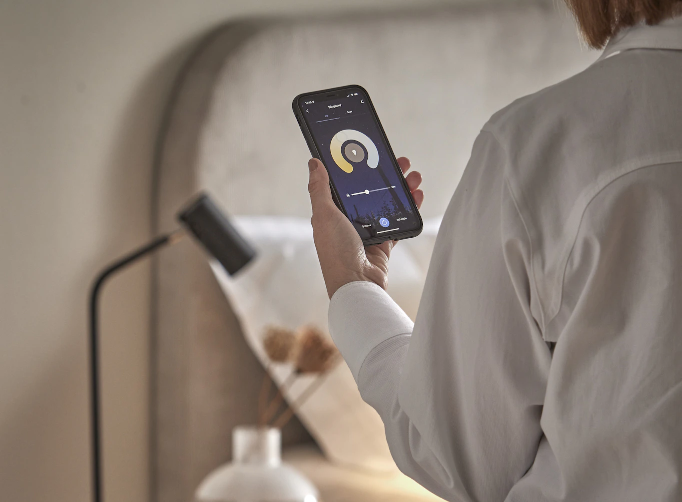 en person håller upp och visar appen för mio smarta hem