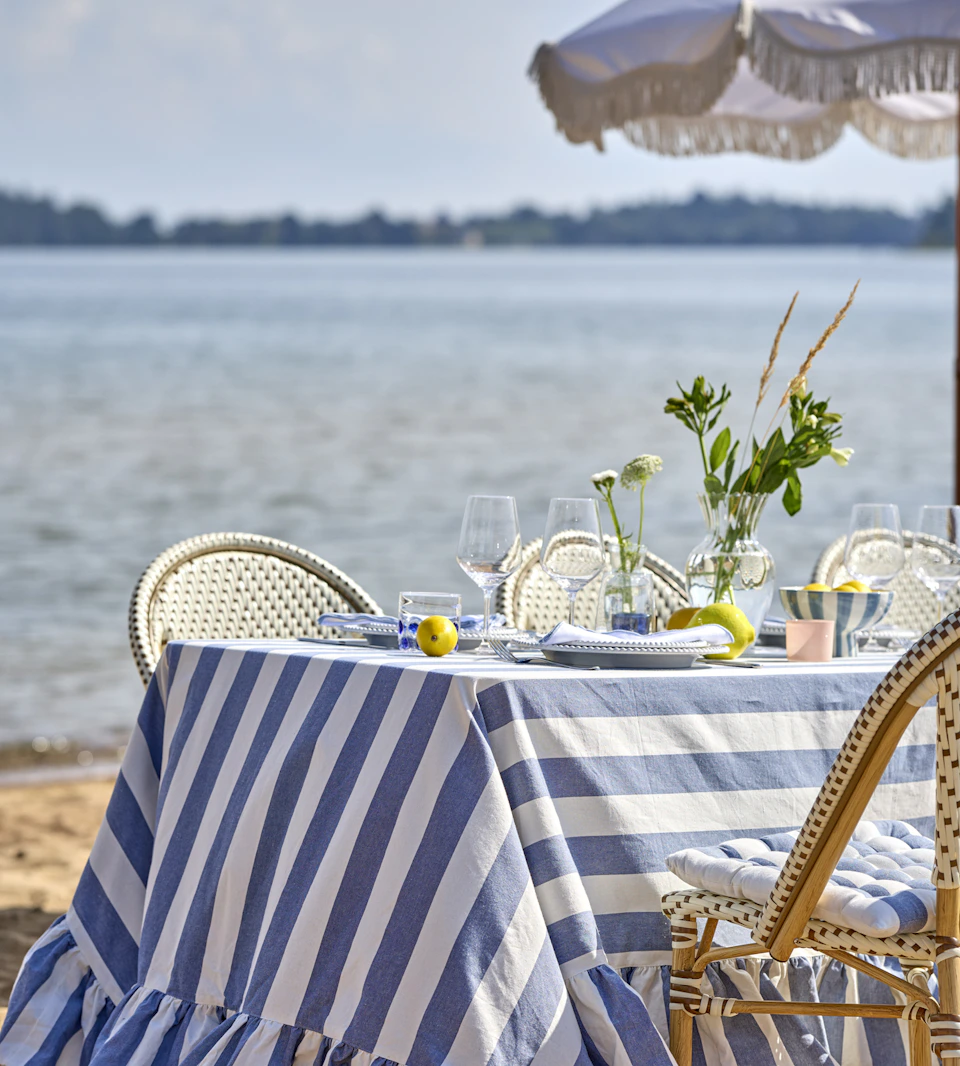 ett bord står dukat på en strand med en blårandig duk