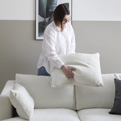 en person puffar till kudden i en soffa