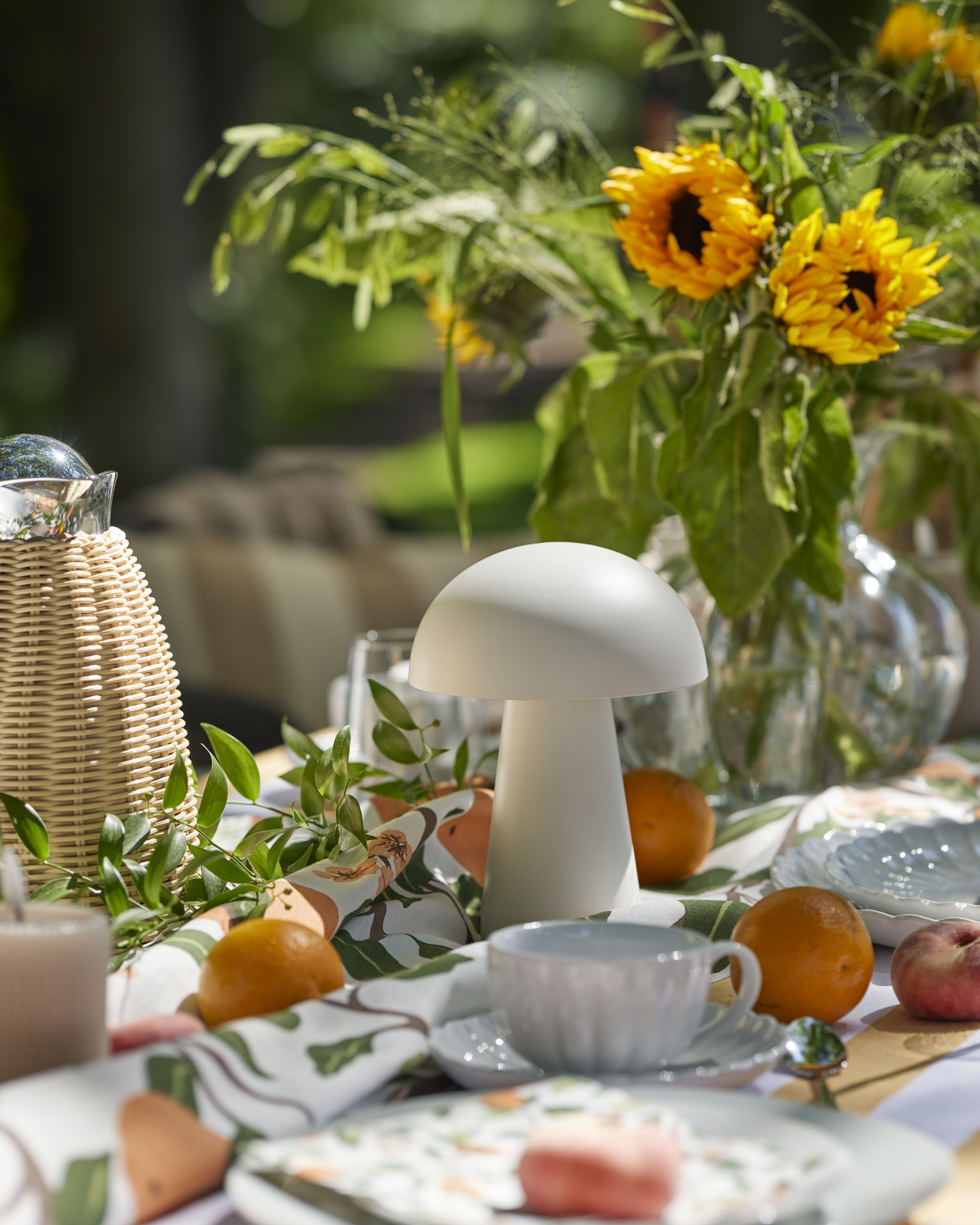 en vit portabel lampa står på ett dukat bord utomhus