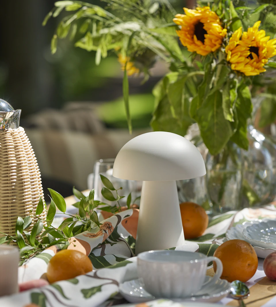 en vit portabel lampa står på ett dukat bord utomhus