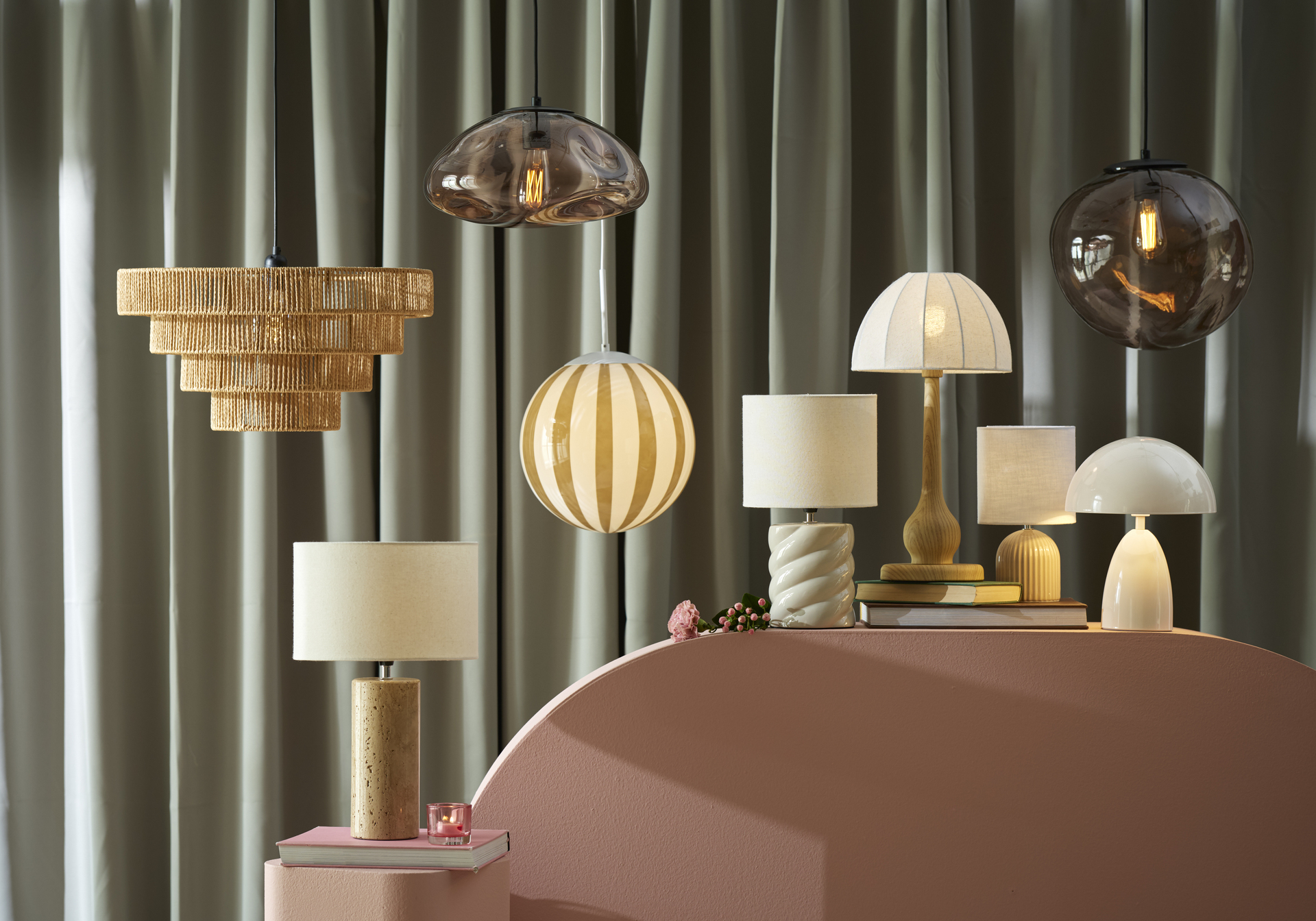 olika sorters lampor står och hänger på en rosa piedestal framför en grön bakgrund