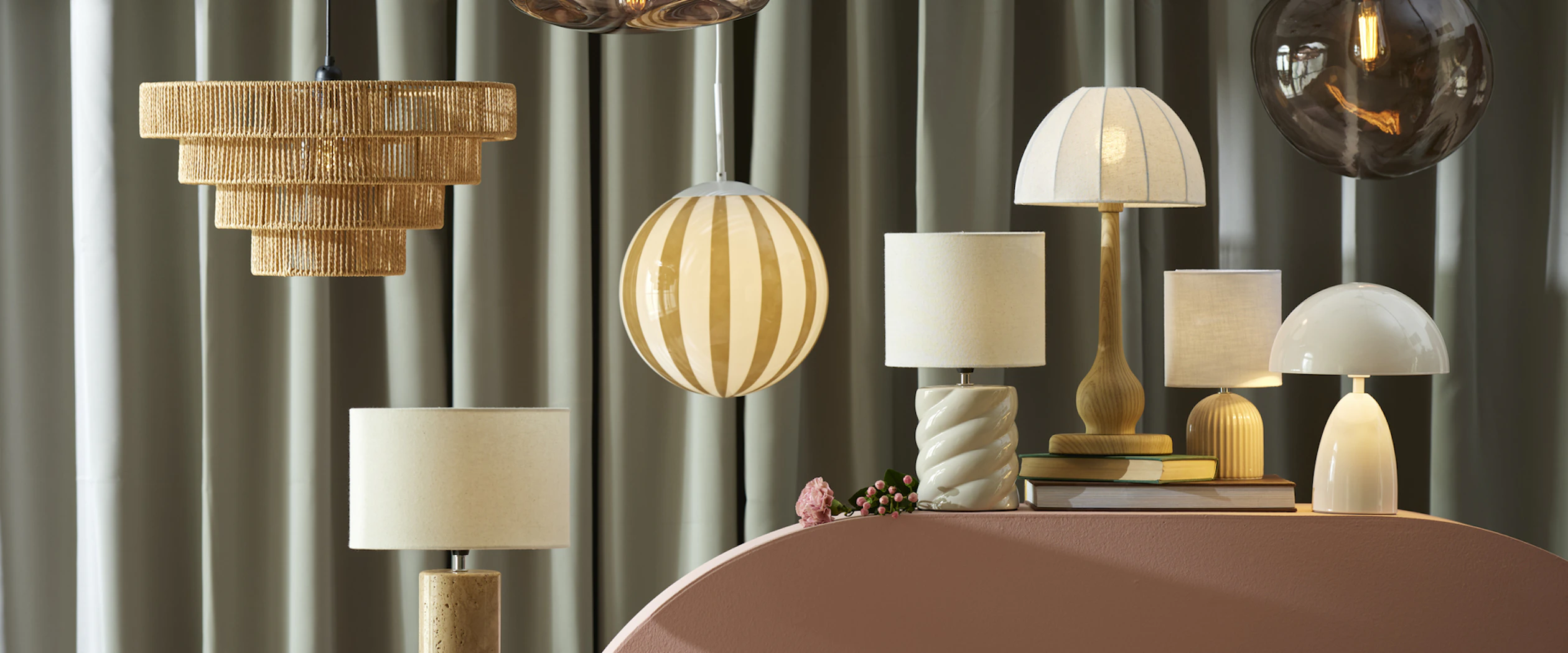 olika sorters lampor står och hänger på en rosa piedestal framför en grön bakgrund