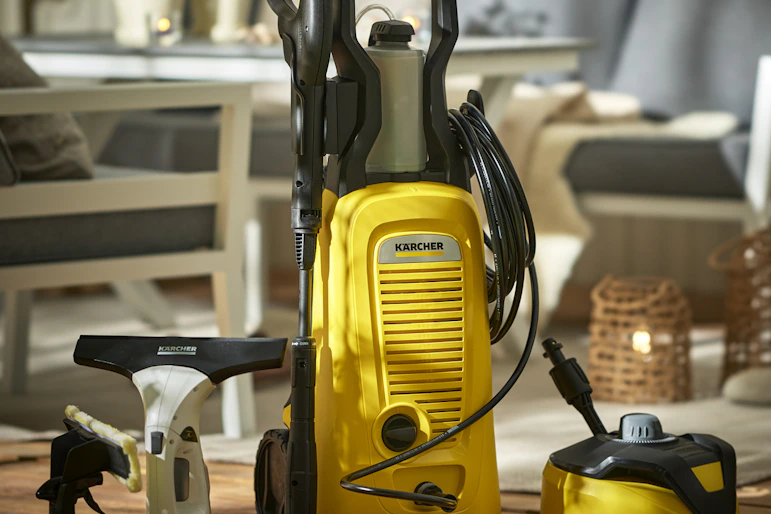 Produkter för rengöring från Kärcher står uppställda på ett trallgolv i en uteplatsmiljö