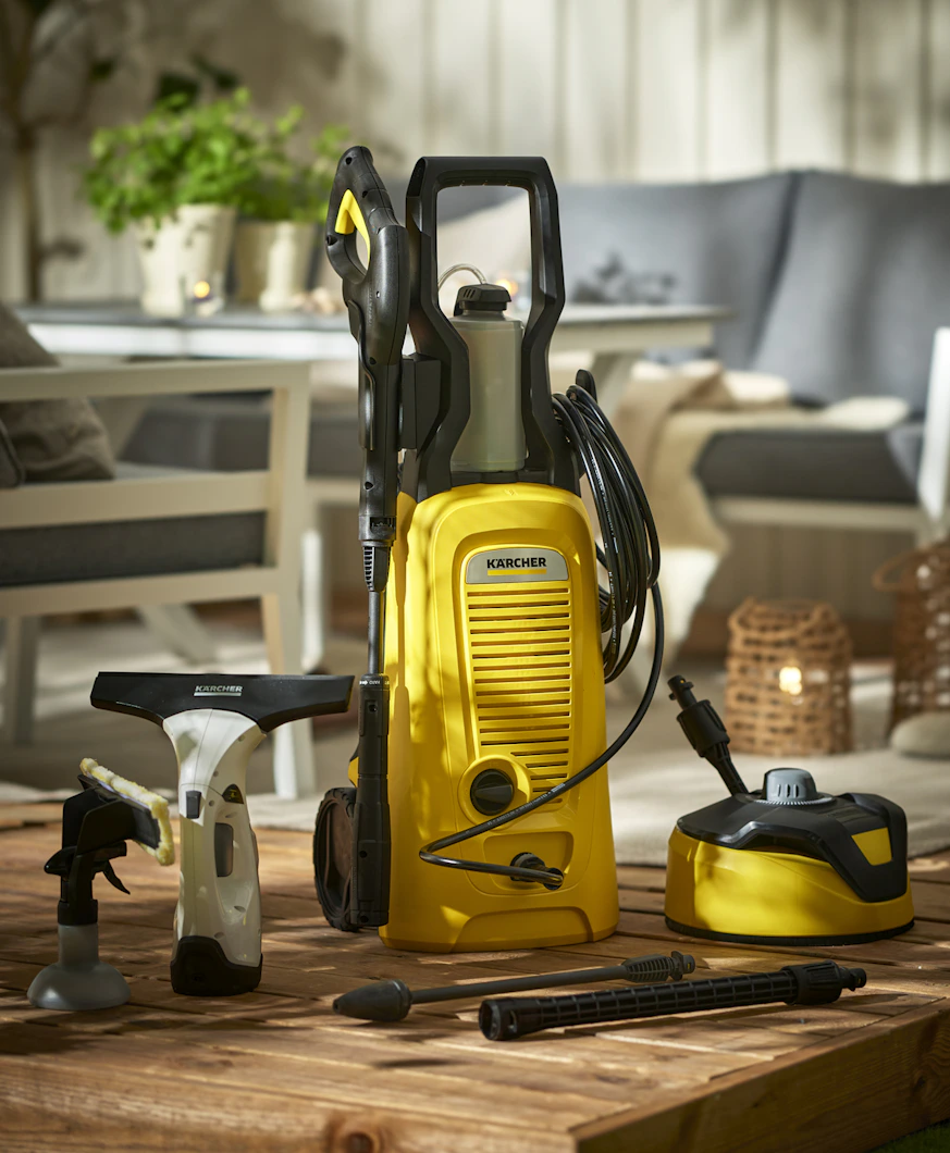 Produkter för rengöring från Kärcher står uppställda på ett trallgolv i en uteplatsmiljö