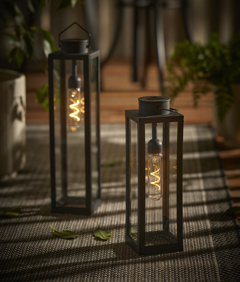 Två svarta ljuslyktor står på en uteplats i skymningen