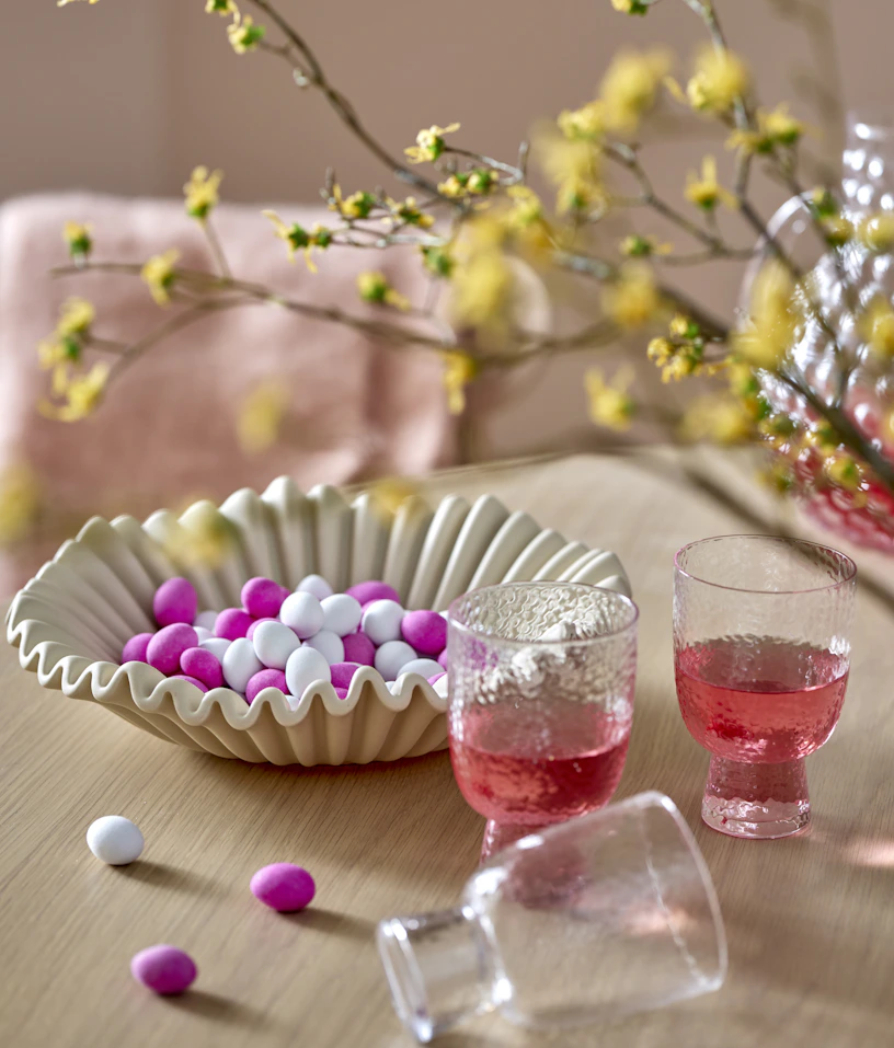 ett beiget fat med godis och dricksglas står på ett ljust matbord i trä