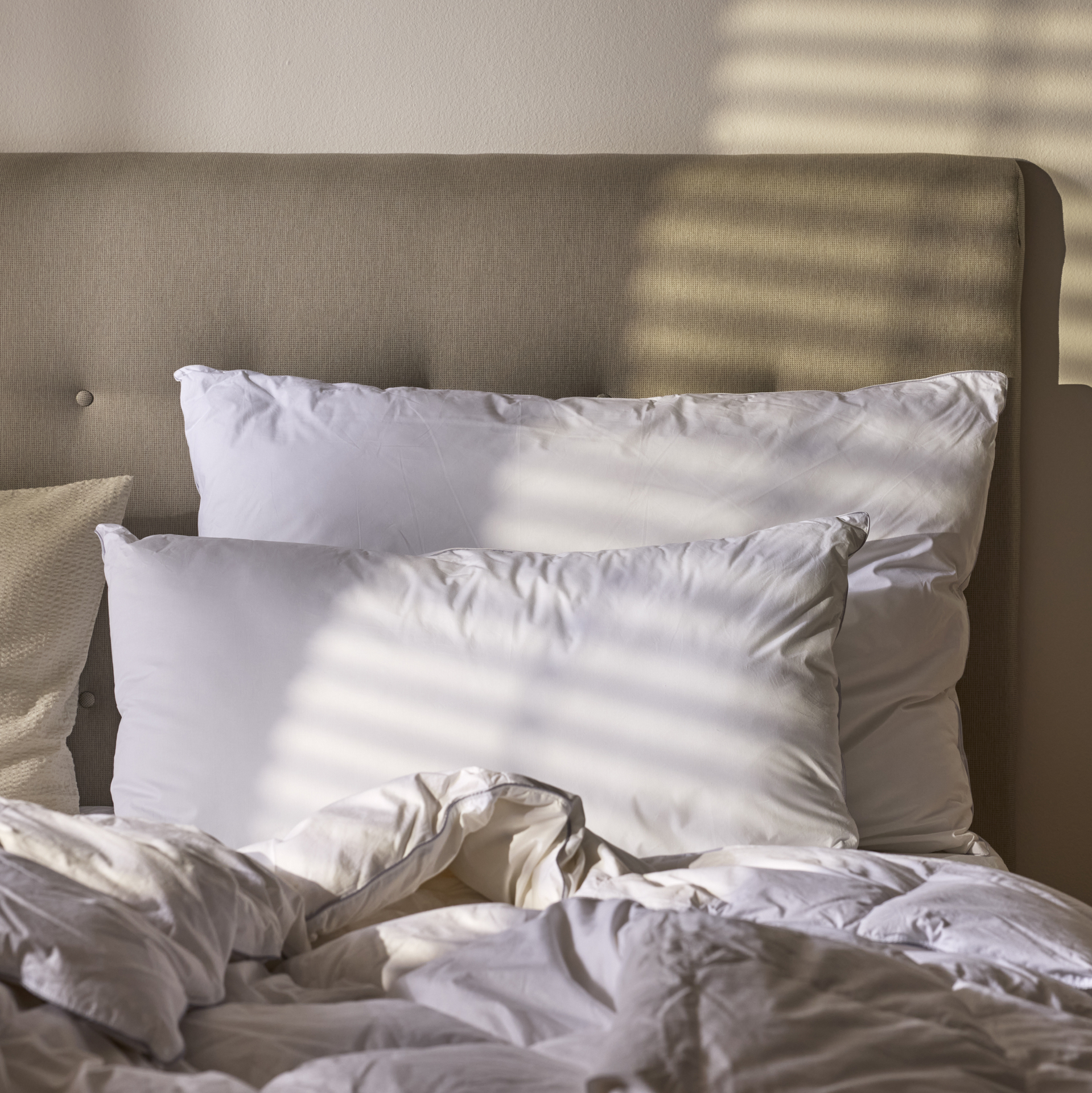 Två vita stora kuddar ligger mot en sänggavel