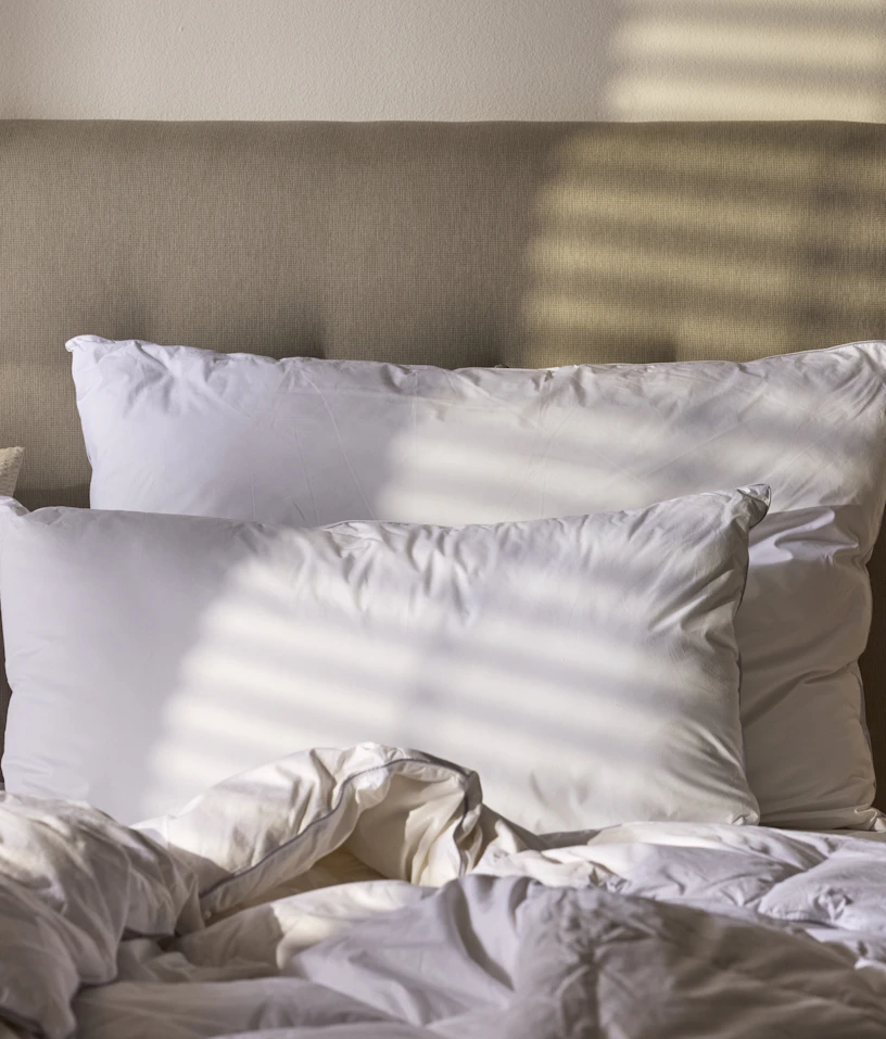 Två vita stora kuddar ligger mot en sänggavel