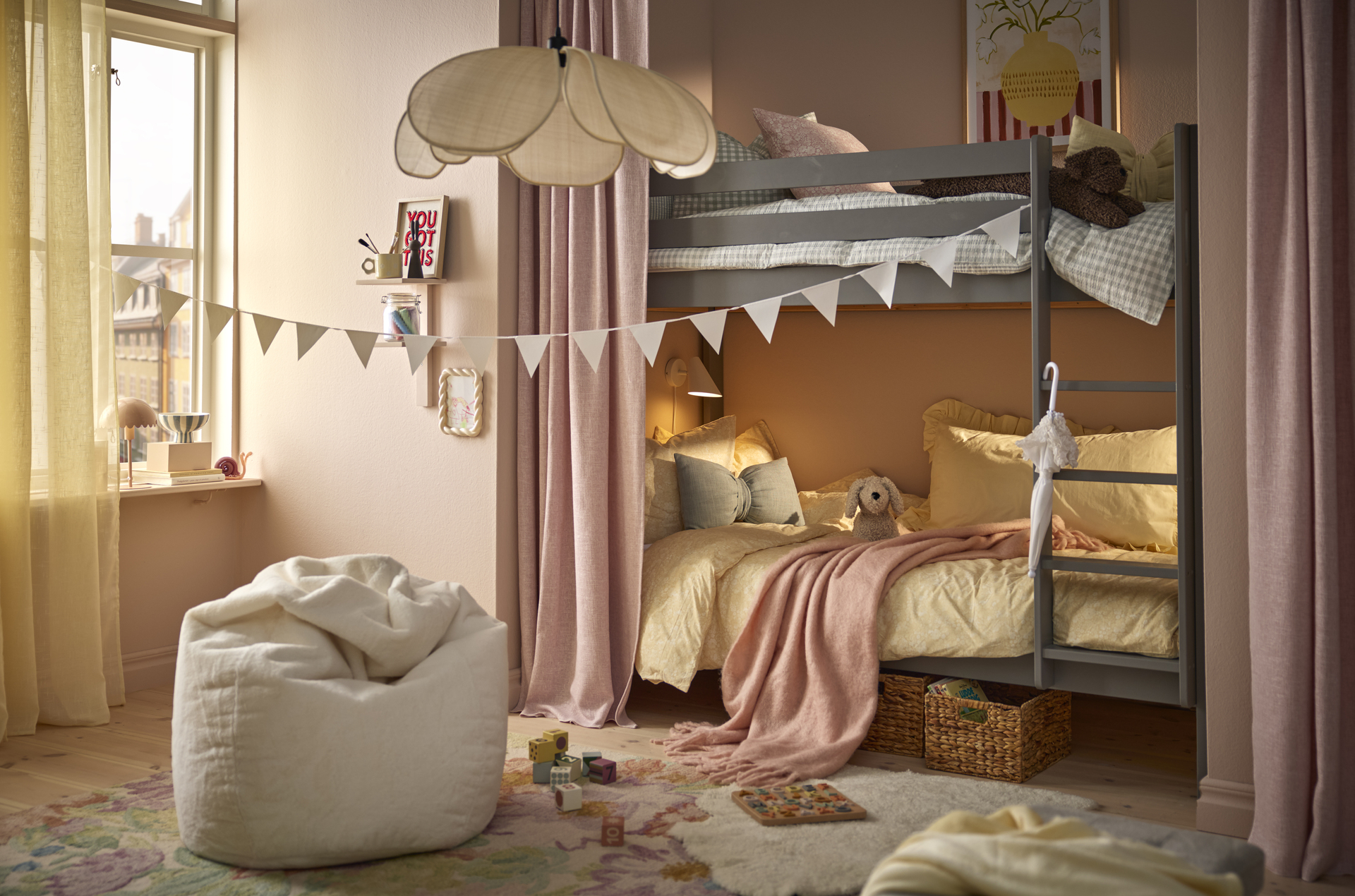 En beige sittsäck står i ett barnrum med rosa väggar och en vimpel hängandes genom rummet