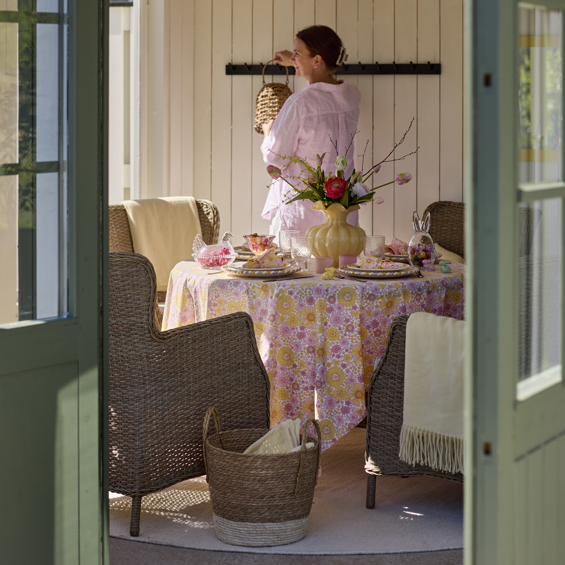 en tjej står i ett uterum bakom ett dukat påskbord