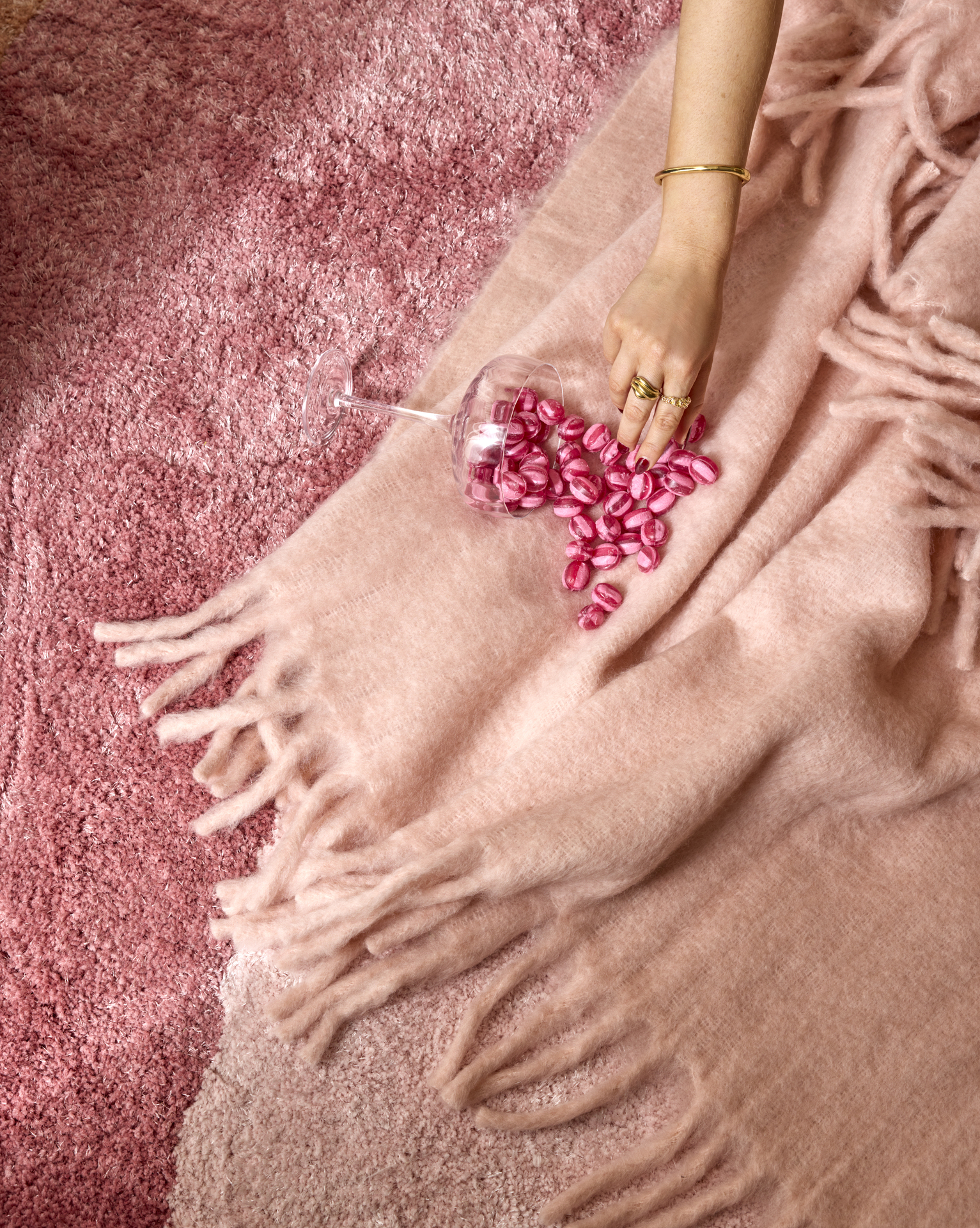 På en rosa pläd ligger en vält skål med rosa godis, som en hand sträcker sig efter.