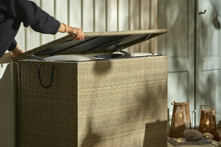 En blond tjej öppnar en dynbox som står intill en husvägg