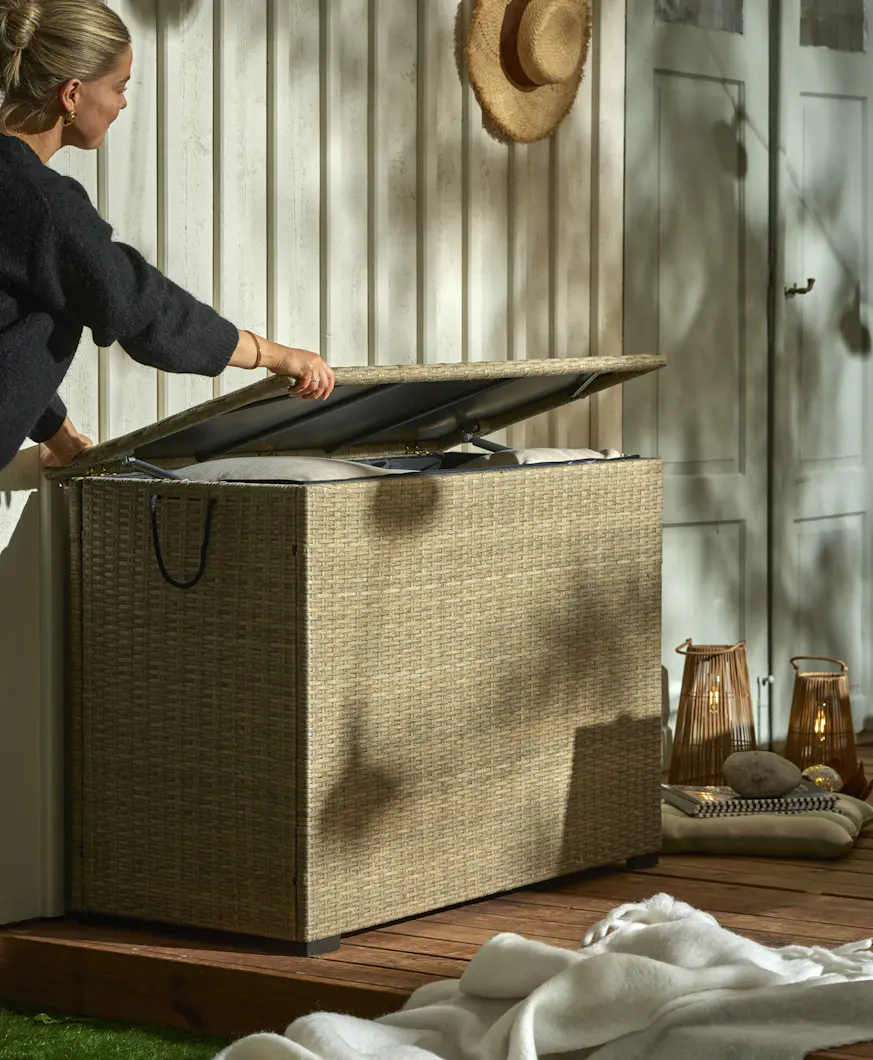En blond tjej öppnar en dynbox som står intill en husvägg