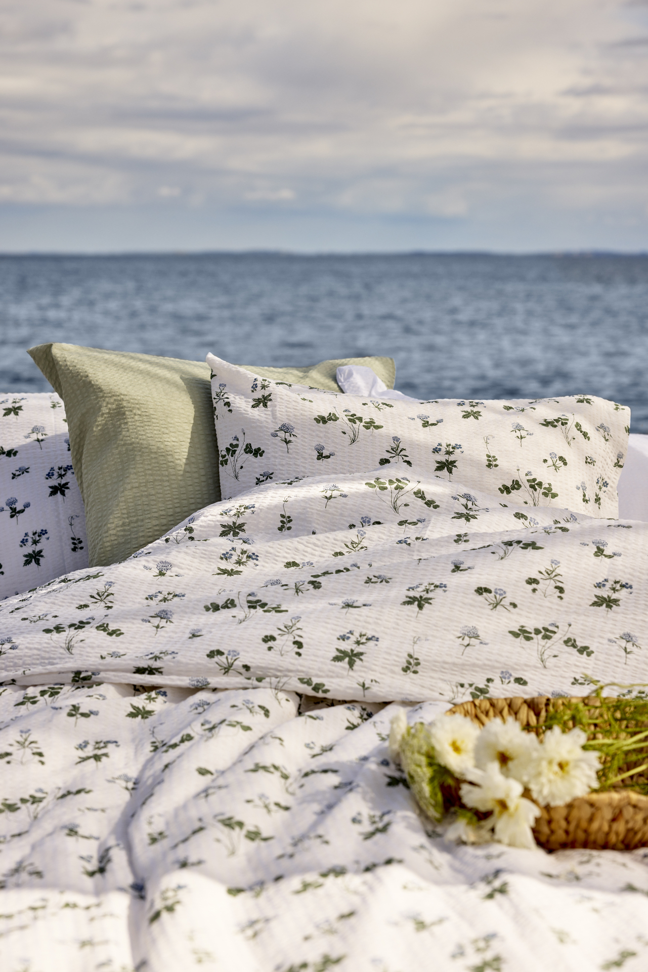 Sköna påslakan i bäckebölja med somrigt blommiga mönster är uppbäddat på en brygga framför en sjö