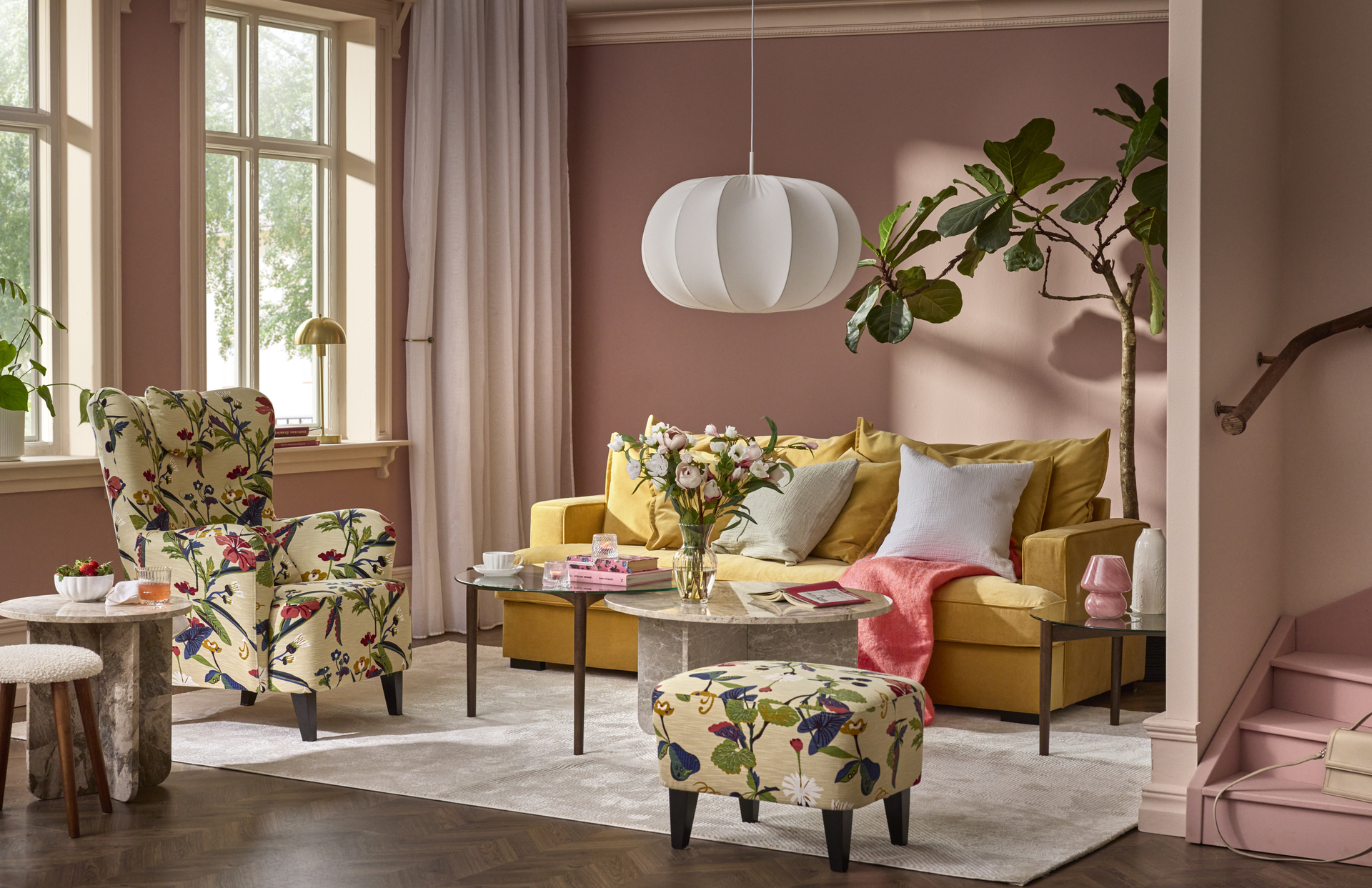 I ett rosa vardagsrum står en fåtölj i blommigt mönster intill ett sidobord i marmor.
