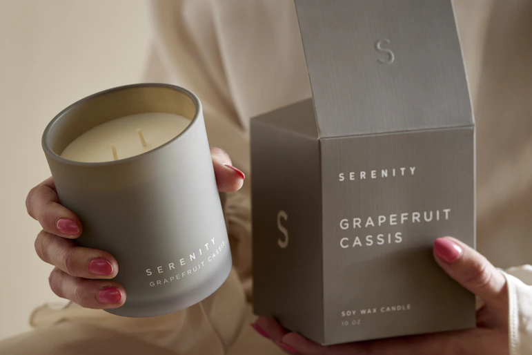 En kvinna håller i ett doftljus med doften Grapefruit Cassis.