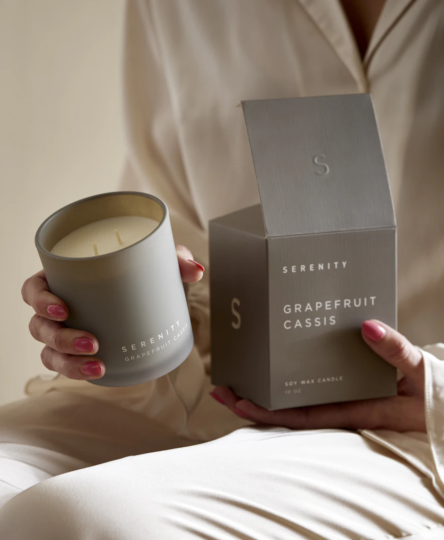 En kvinna håller i ett doftljus med doften Grapefruit Cassis.