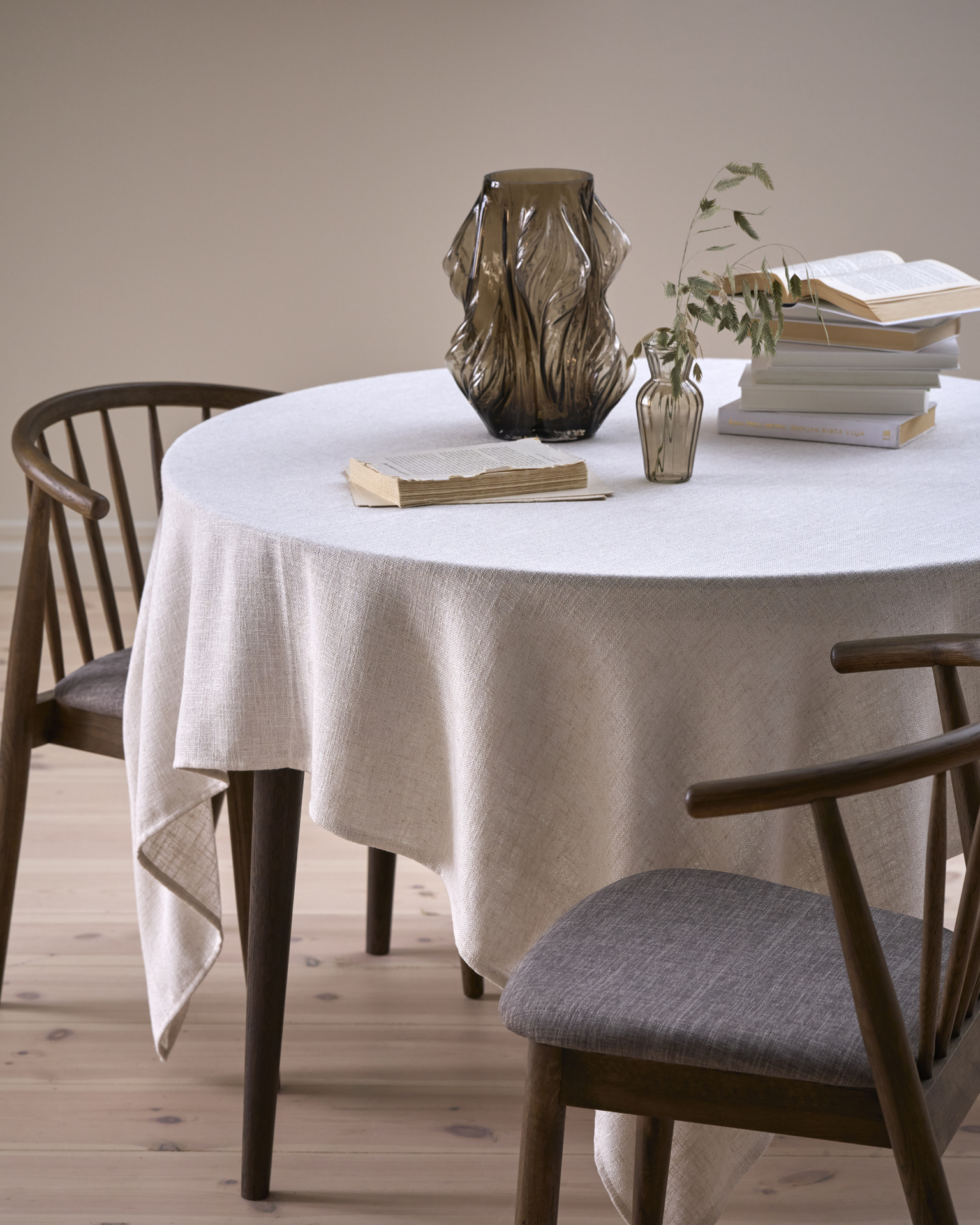 På ett runt bord finns en vit duk, en brun vas och några böcker.