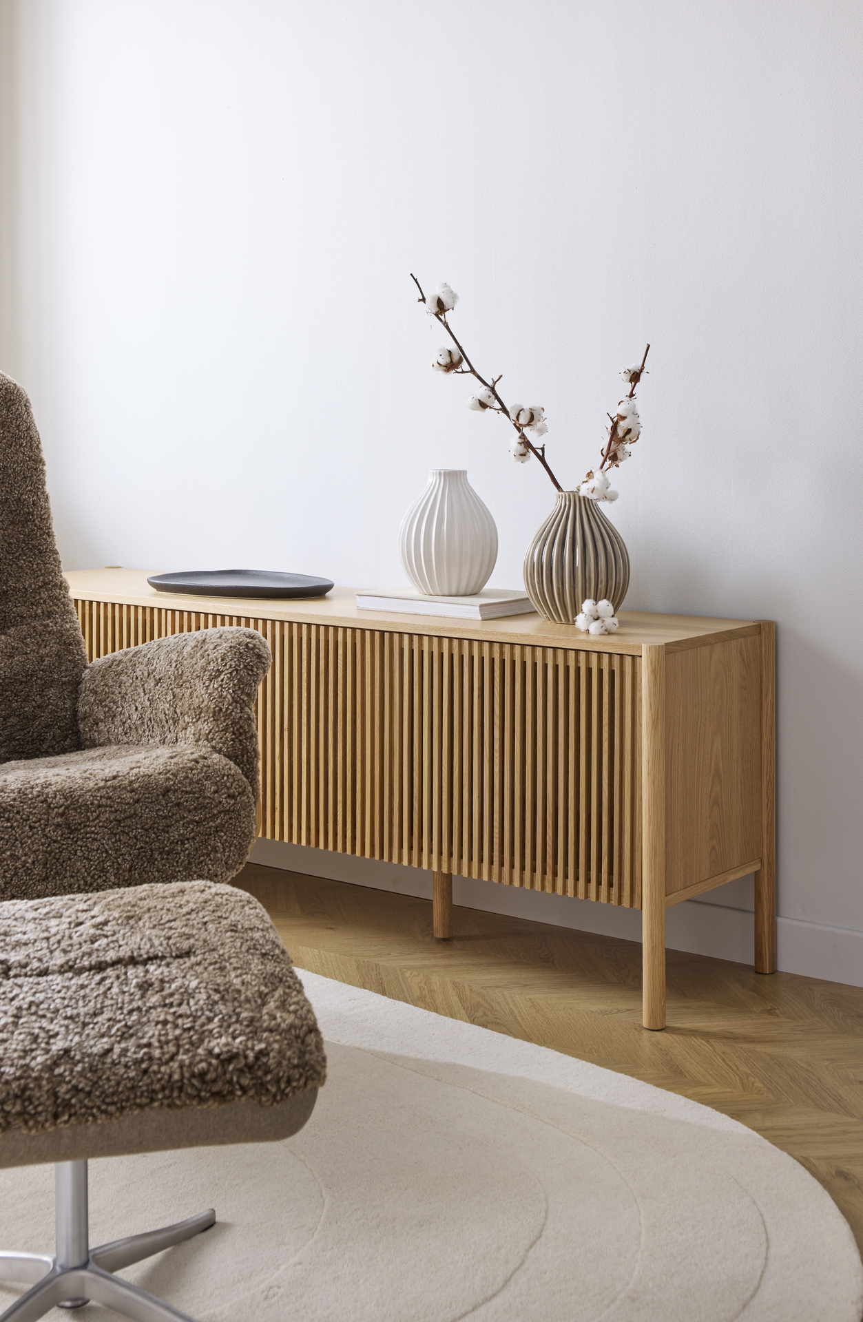 En tv-bänk med ribbad front i ljust trä står framför en vit vägg.