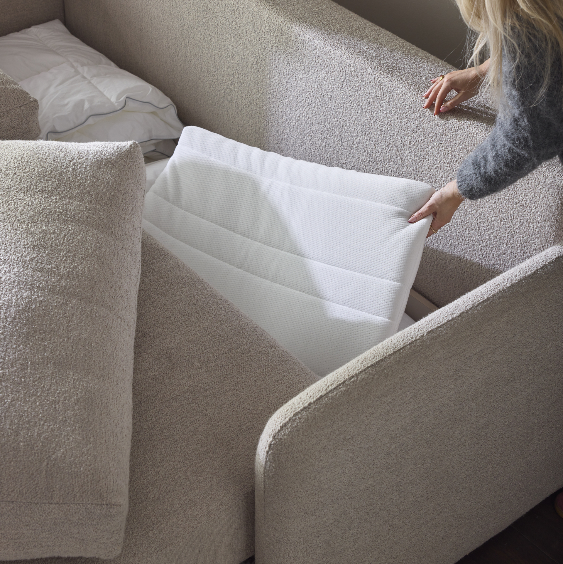 Bild som visar en beige bäddsoffa med svart förvaring