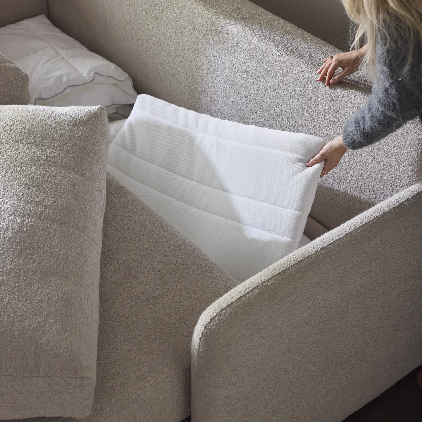 Bild som visar en beige bäddsoffa med svart förvaring