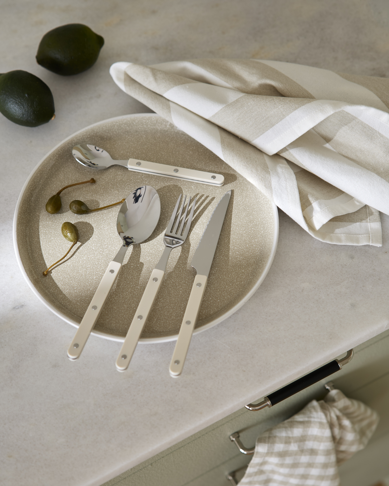På en beige tallrik ligger bestick i retrodesign