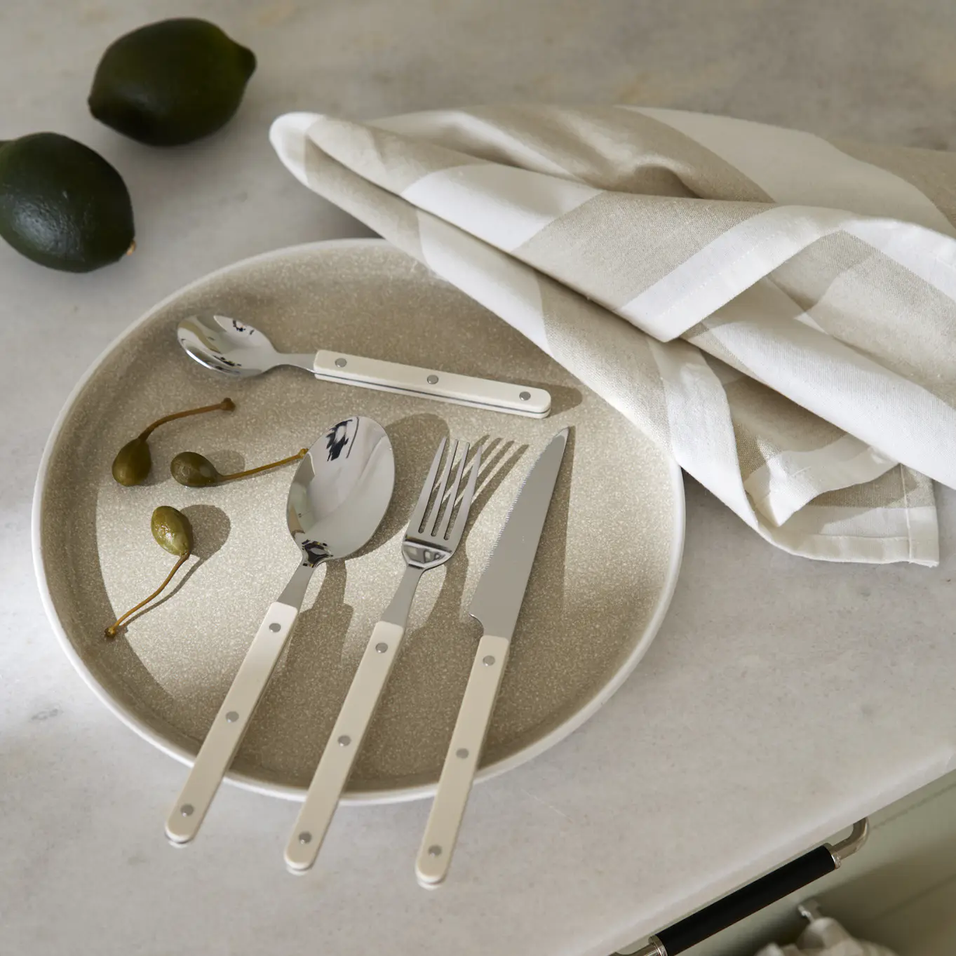 På en beige tallrik ligger bestick i retrodesign