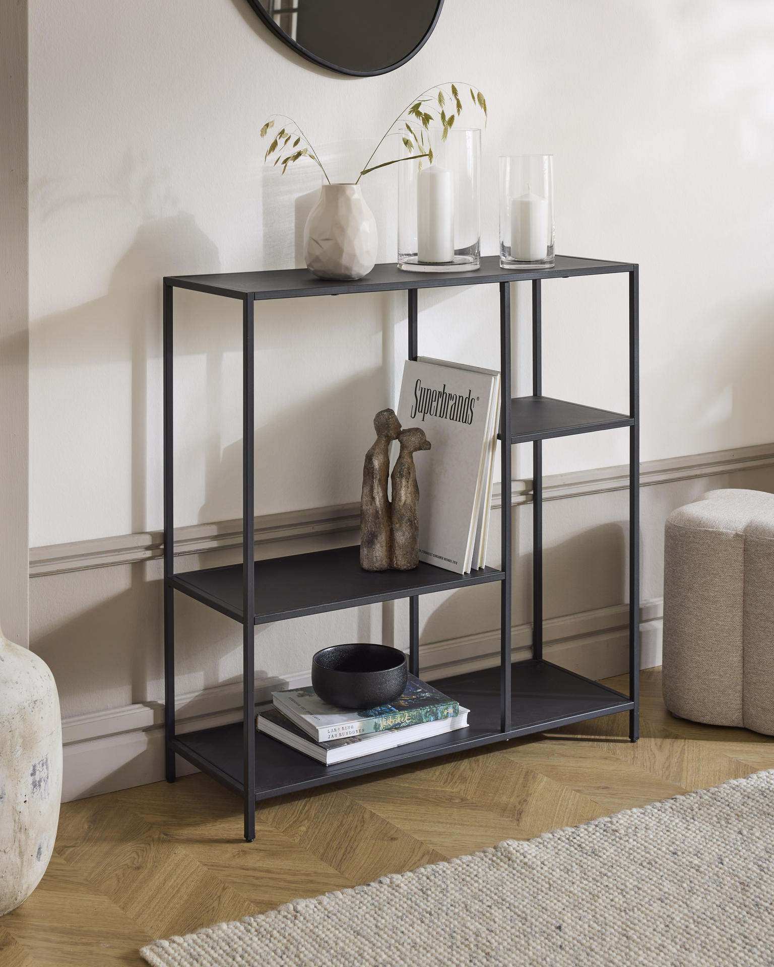 en svart hylla med olika dekorationer står framför en vit vägg