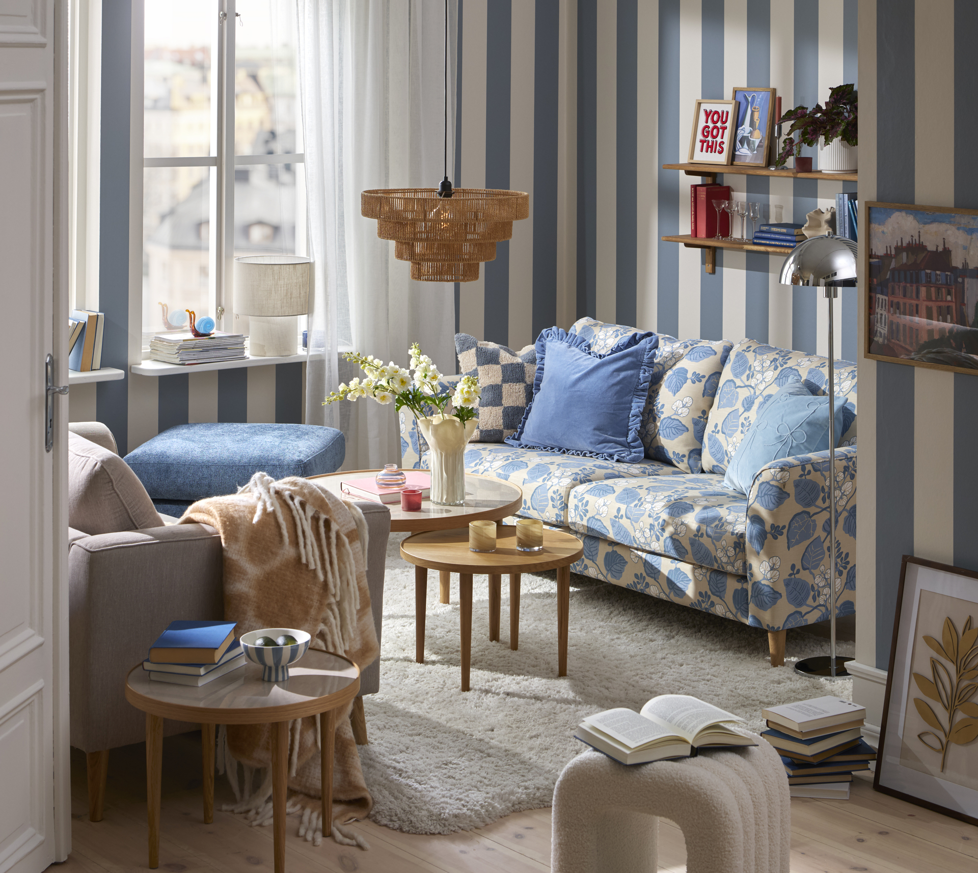 En blåmönstrad soffa står i ett lekfullt inrett vardagsrum med blåvit randig tapet.
