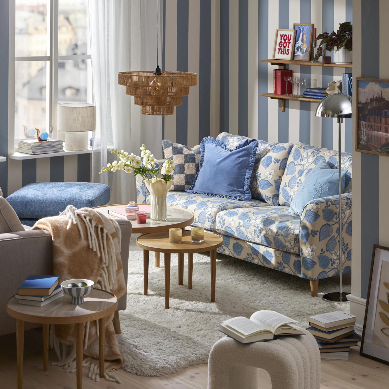 En blåmönstrad soffa står i ett lekfullt inrett vardagsrum med blåvit randig tapet.