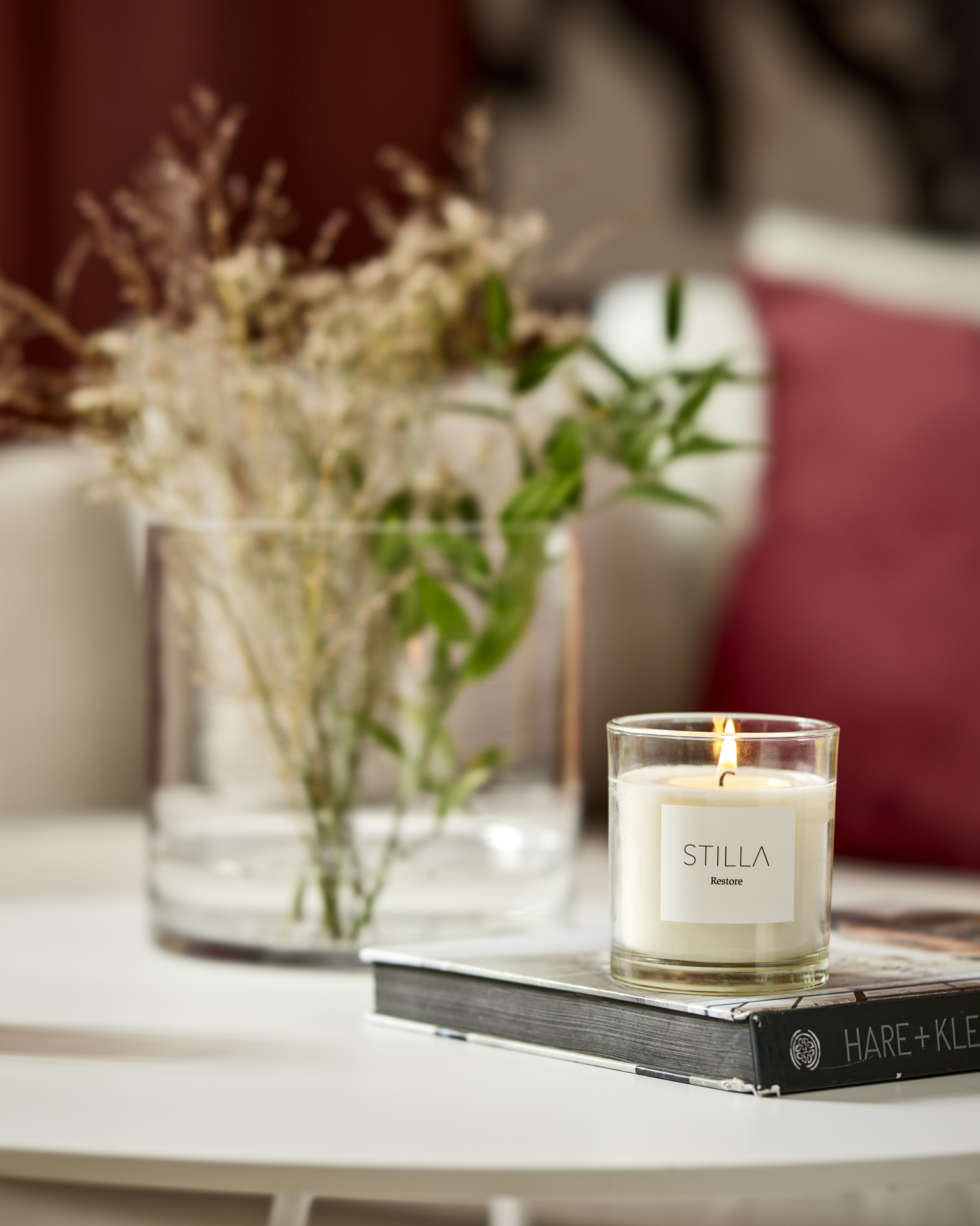 På ett bord står ett stilrent doftljus ovanpå en bok