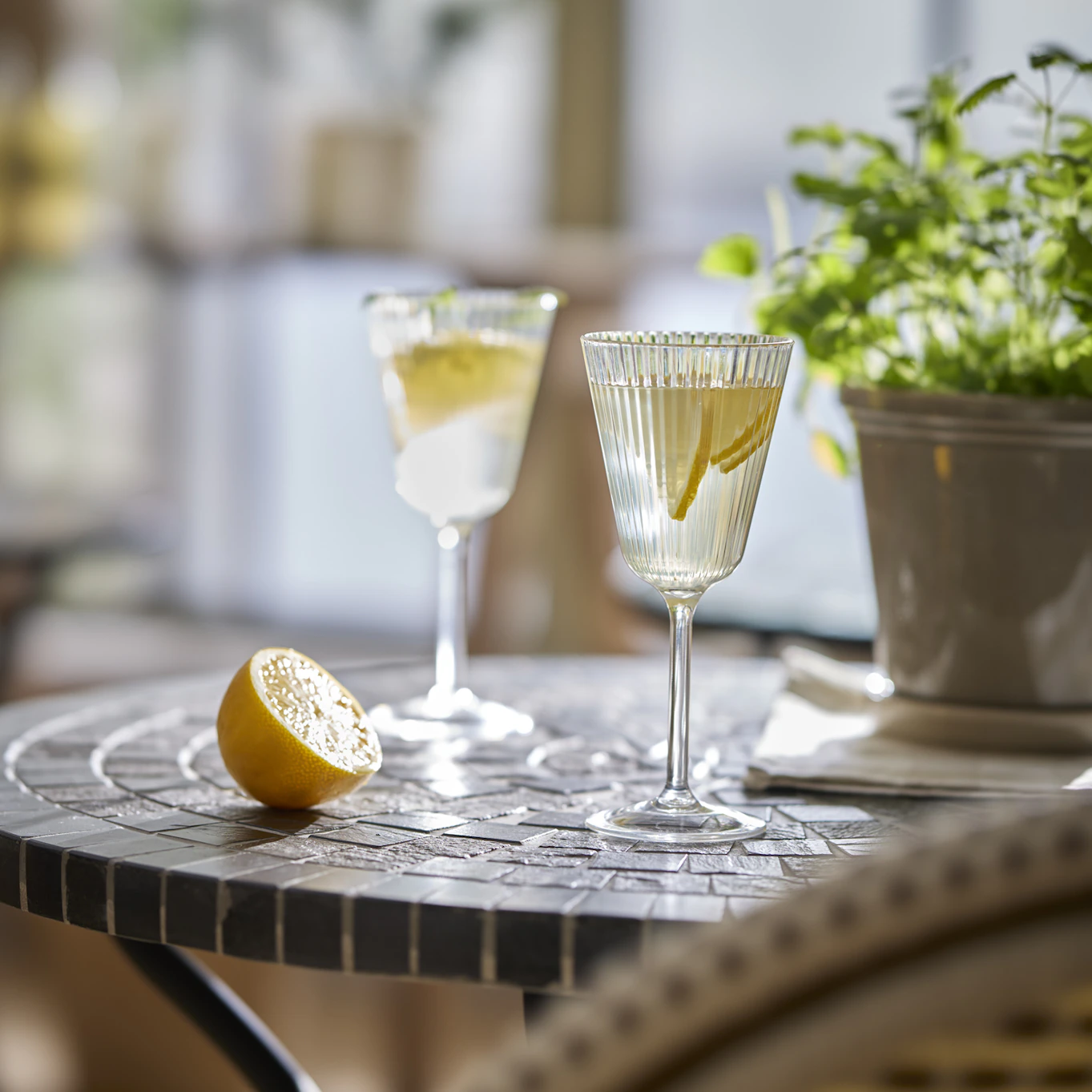 På ett bord i mosaik i ett uterum står två glas fyllda med lemonad