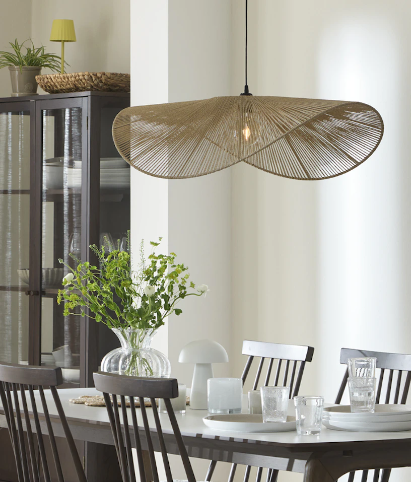 En stor lampa i organisk for hänger över ett matbord