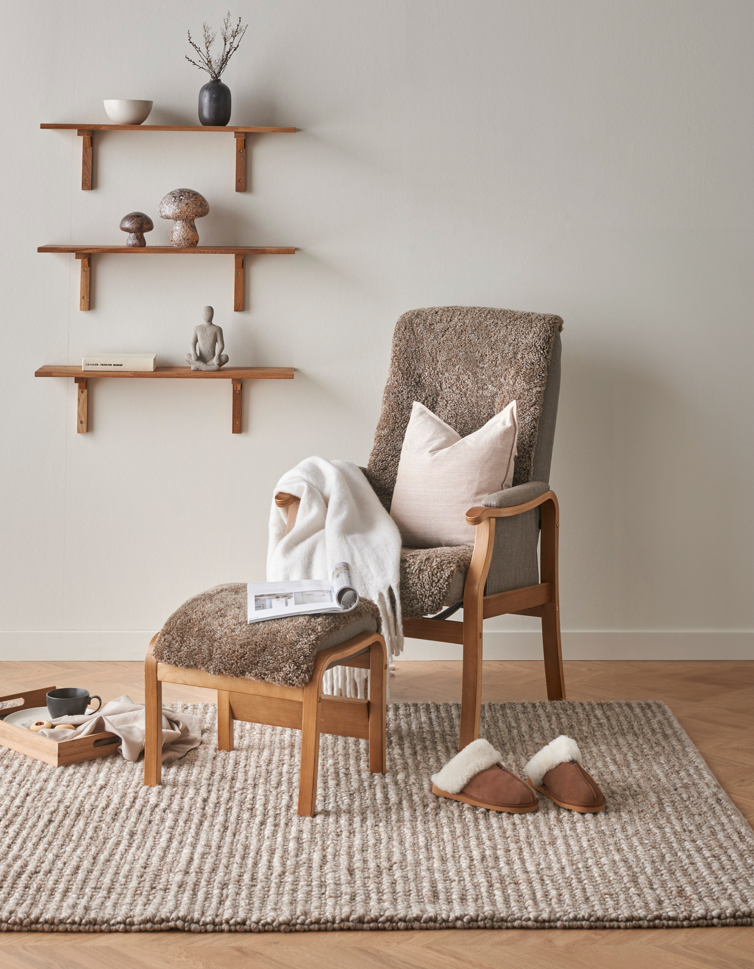 I ett beiget rum står en fåtölj i brunt fårskinn och ek