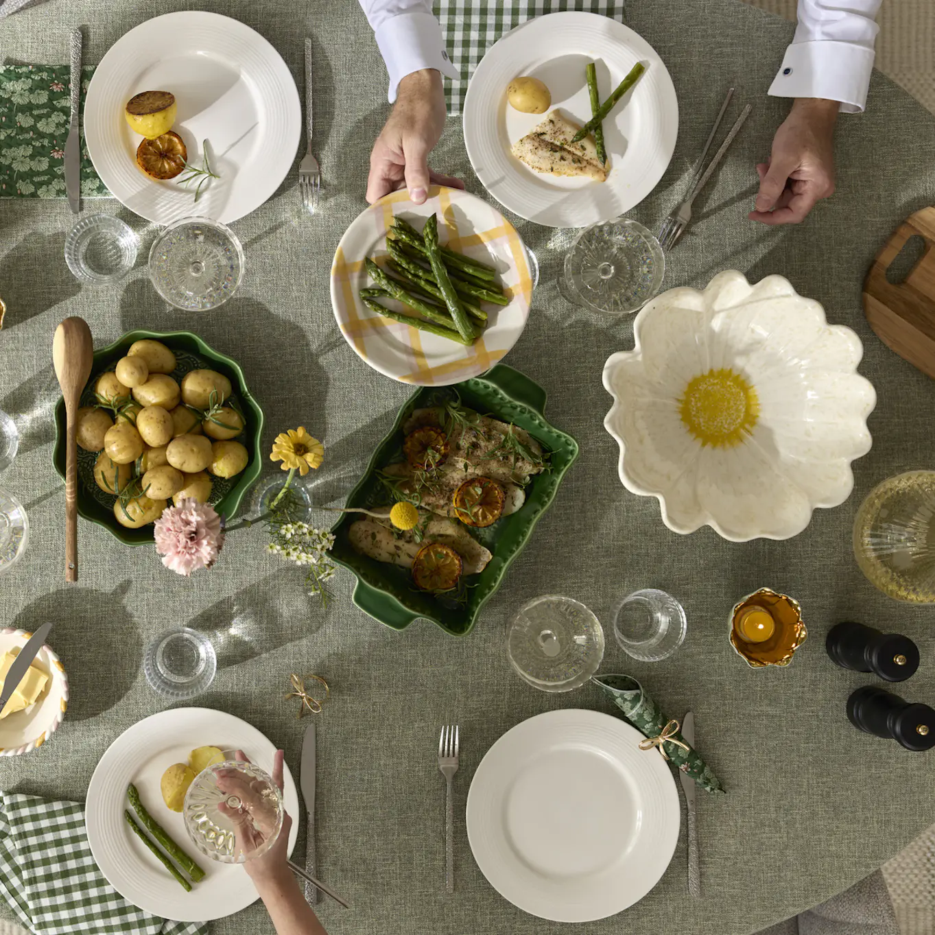 På ett bord klätt i en grön duk är fullt av fat och tallrikar av olika modeller