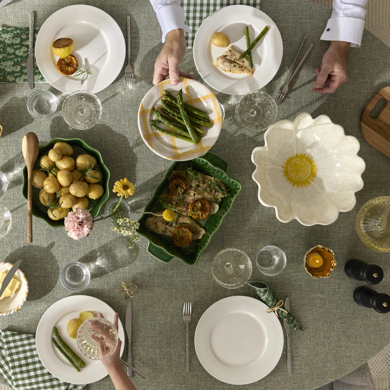 På ett bord klätt i en grön duk är fullt av fat och tallrikar av olika modeller