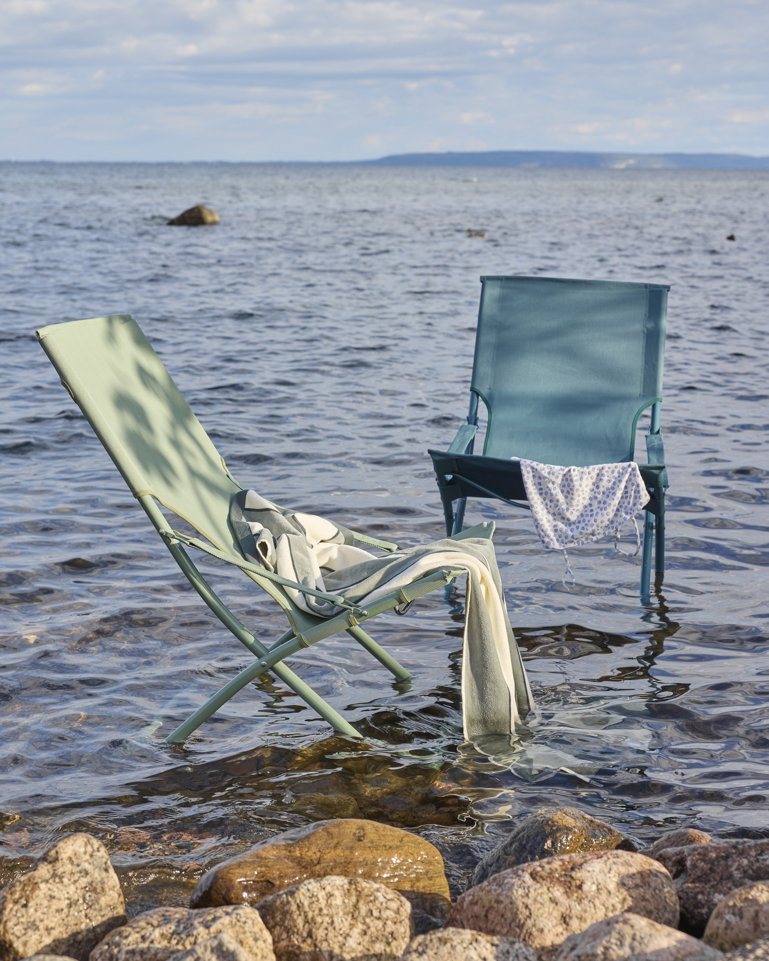 I grunt vatten står en grön och en turkos fällbar solstol